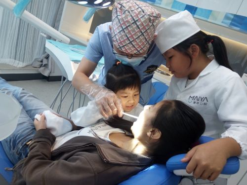 小牙医在医生的指导下为家长检查牙齿